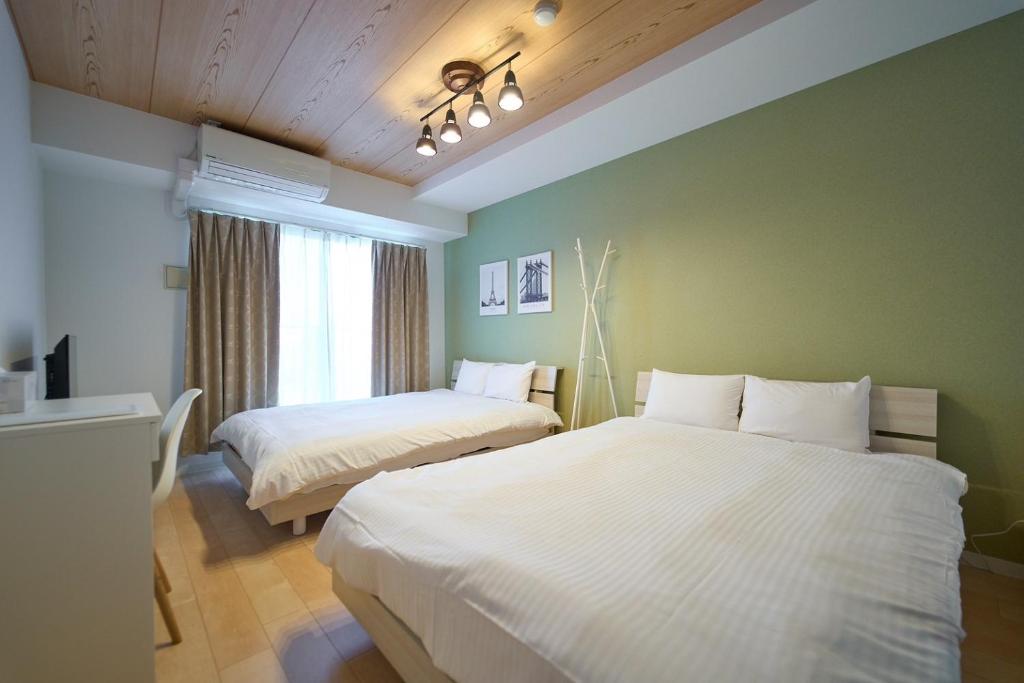 two beds in a room with green walls at Queen's Park 空港直通 新今宮駅 通天閣 新世界 in Osaka