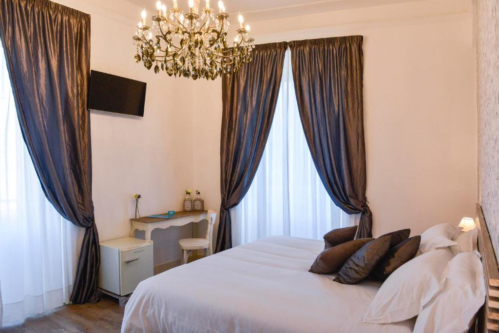 1 dormitorio con 1 cama con cortinas y lámpara de araña en Adelina Guesthouse en Roma