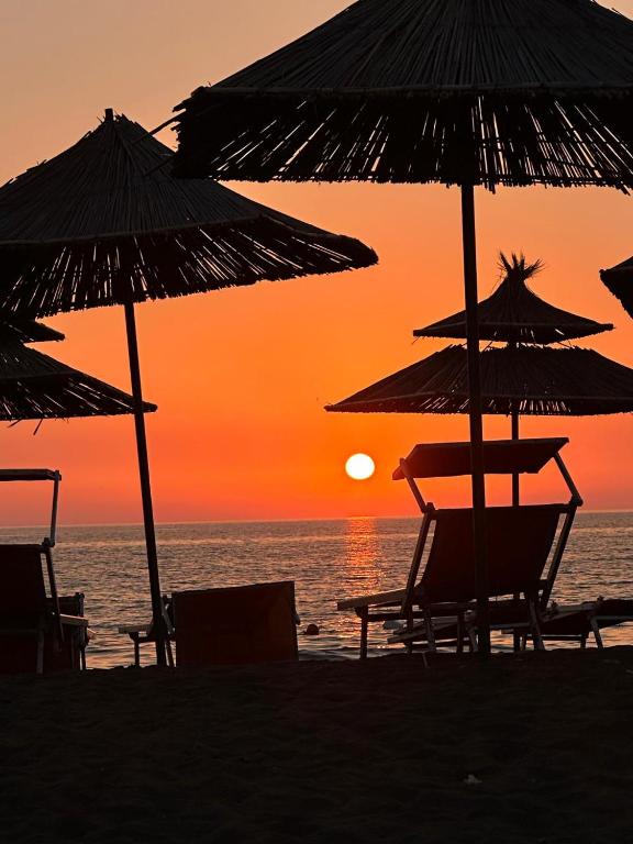 two chairs and umbrellas on the beach at sunset at Bert-House close to the sea in Lezhë