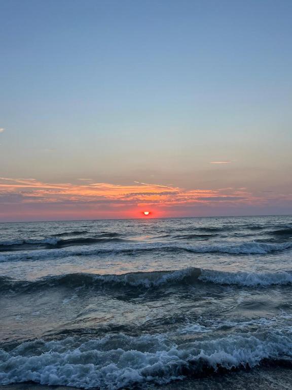 a sunset over the ocean with waves at Bert-House close to the sea in Lezhë