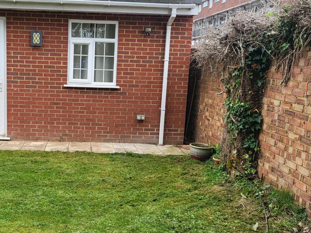 a brick house with a window and a yard at Nest & Rest En-Suite in Ashford