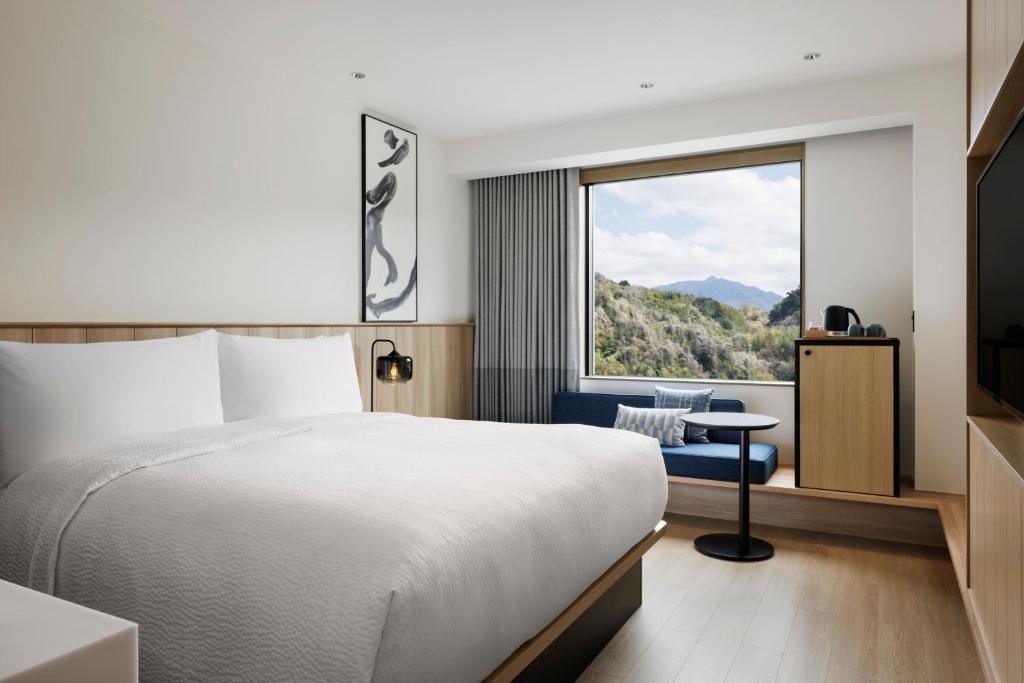 垂水市にあるFairfield by Marriott Kagoshima Sakurajimaのベッドと大きな窓があるホテルの部屋