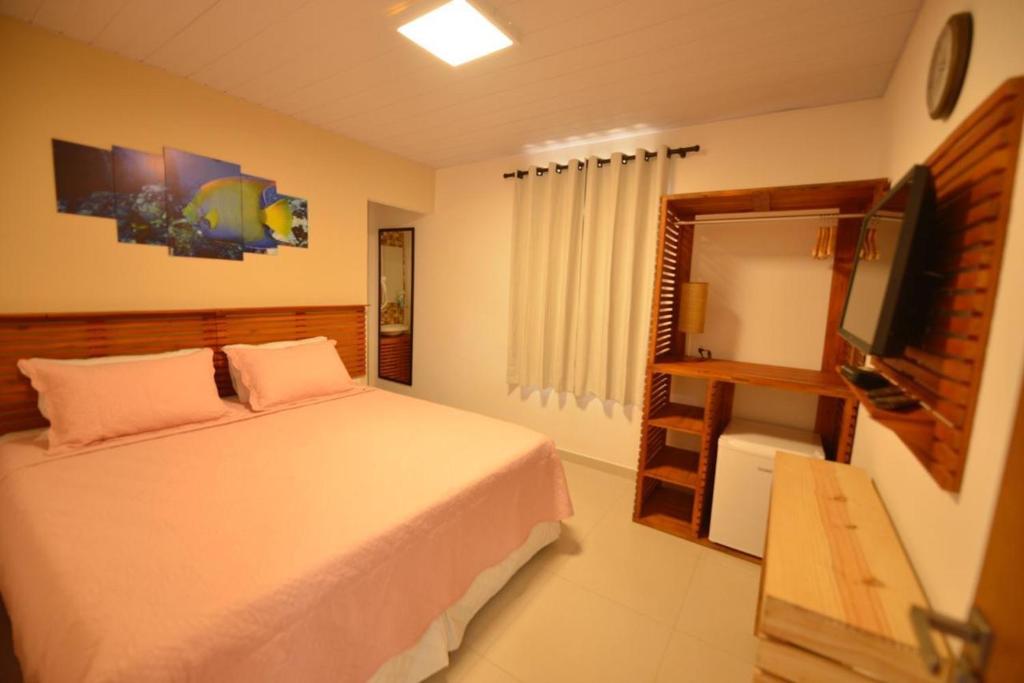 una camera da letto con un letto e una TV a schermo piatto di Pousada Flôr do Atlântico a Fernando de Noronha