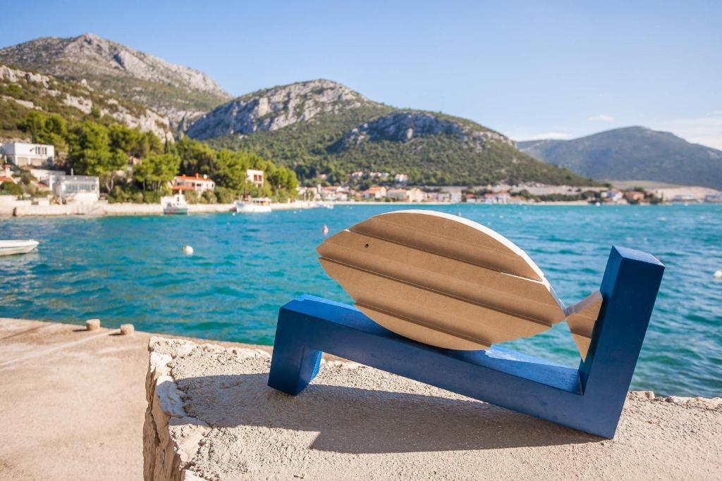 a bench with a surfboard on it next to the water at Apartments Katica in Klek
