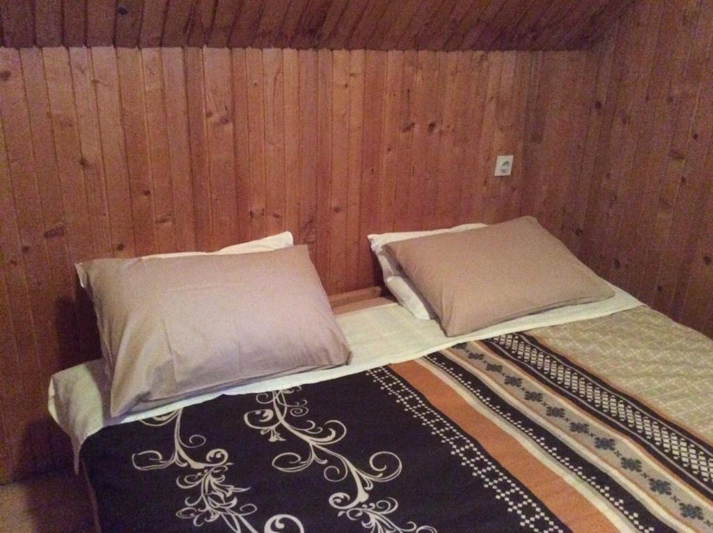a bed with two pillows in a room with wooden walls at Holiday Home Stevas in Žabljak