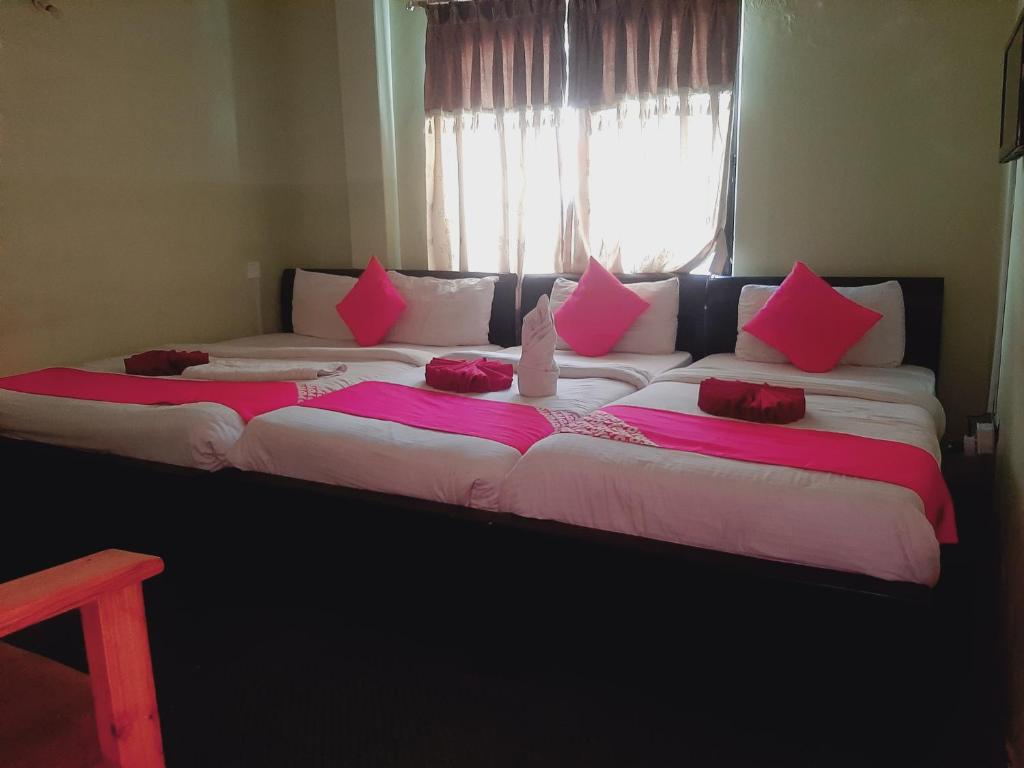 due grandi letti con cuscini rosa sopra in una stanza di Hotel Lake n Yeti a Pokhara