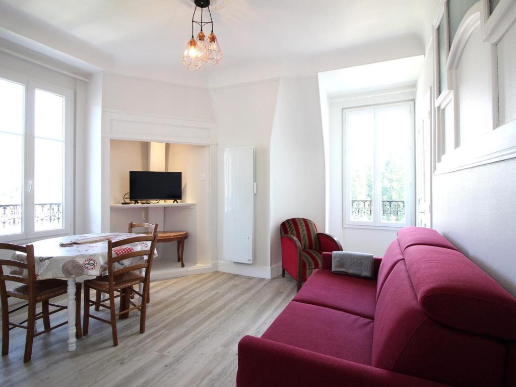 un salon avec un canapé rouge et une table dans l'établissement T2 Confortable avec WiFi proche thermes - FR-1-608-274, à La Bourboule