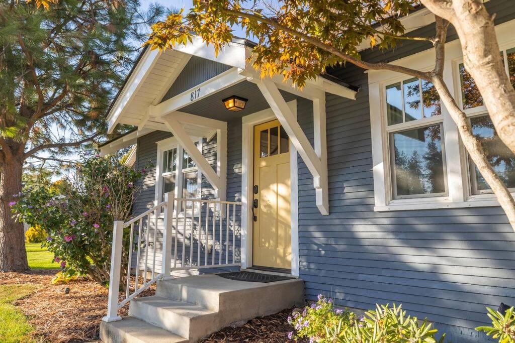 a blue house with a yellow door and stairs at Charming Cozy Cottage with Hot Tub in Coeur d'Alene