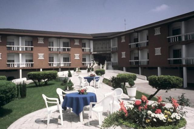 un patio con mesas y sillas blancas y un edificio en Hotel Park Venezia, en Stra