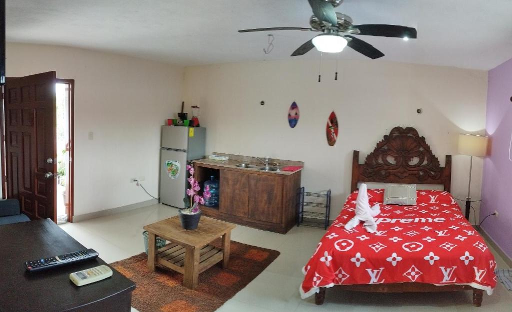 a bedroom with a red bed and a ceiling fan at Gacelita Cozumel in Cozumel