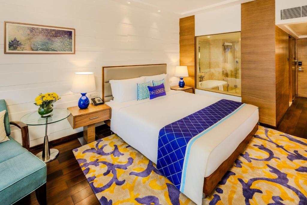 a bedroom with a large bed and a blue couch at Vivanta Goa, Panaji in Panaji
