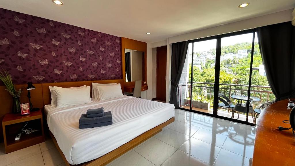 a bedroom with a large bed and a balcony at Coco Mountain View Guest House Hotel in Kata Beach