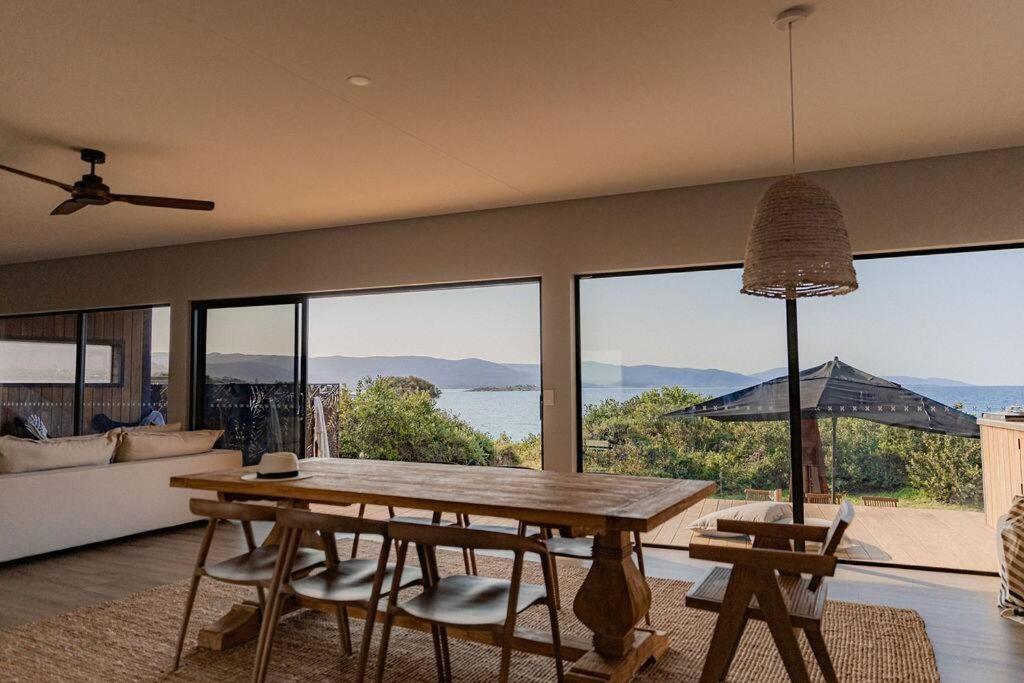 a living room with a wooden table and a large window at Cooinda - on the beach - Bicheno in Bicheno