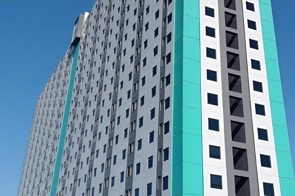 a tall building with many windows at Riverdale Cikarang by Veto Rooms in Tanahbaru