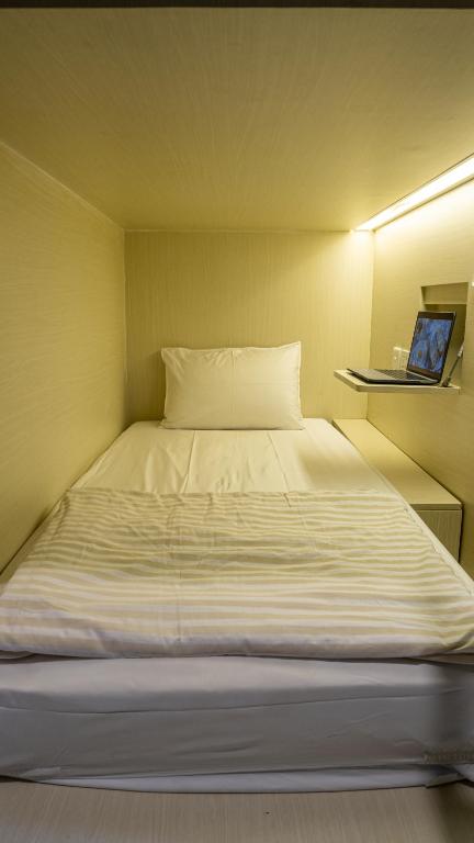 a large white bed in a small room at Aiwan Hostel & Luggage storage in Sanur