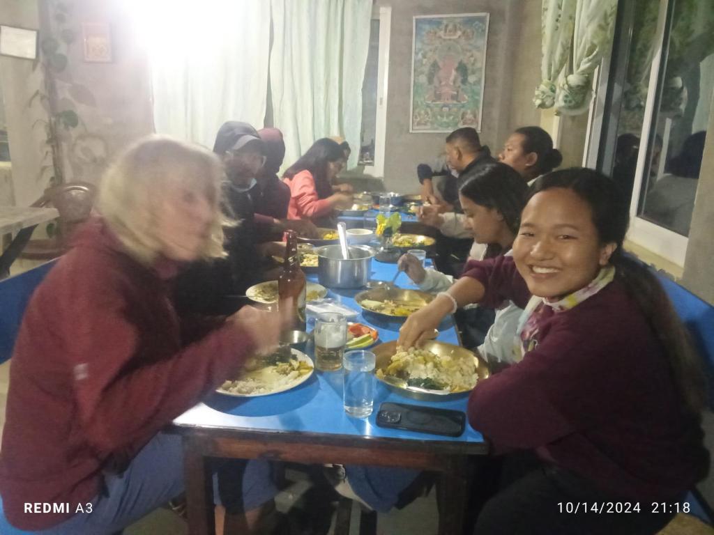 a group of people sitting at a table eating food at Unique point home stay in Nagarkot