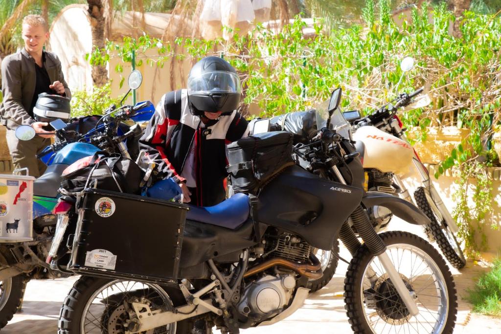 a woman standing next to a motorcycle with a helmet on it at Résidence El Arich in Tozeur