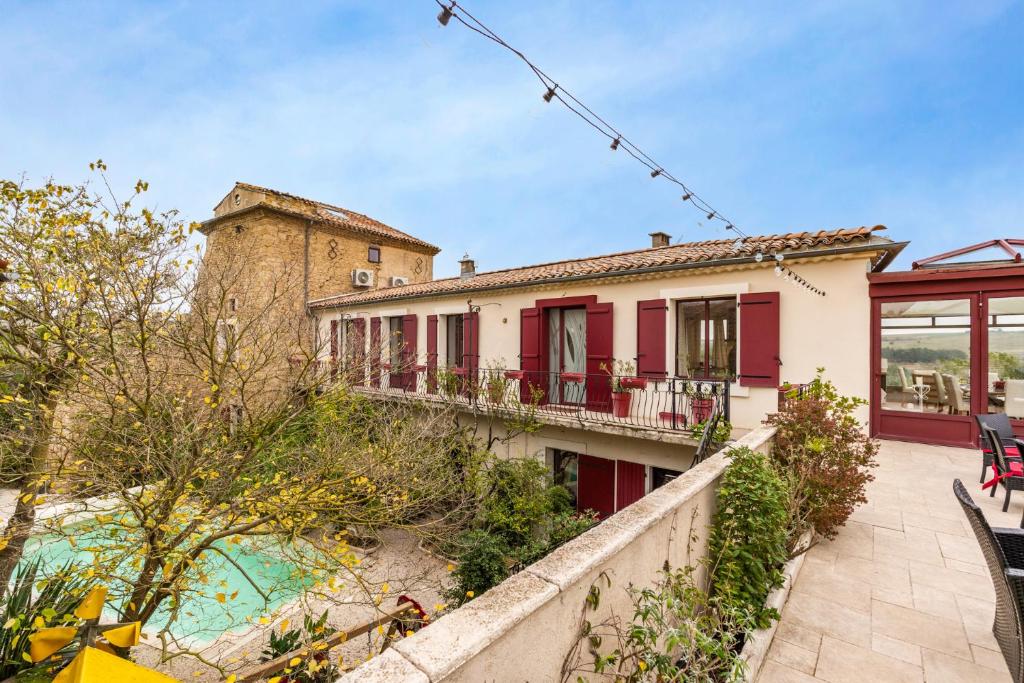 Cette maison dispose de volets rouges et d'un balcon. dans l'établissement château - Le panoramique avec piscine, à Cumiés