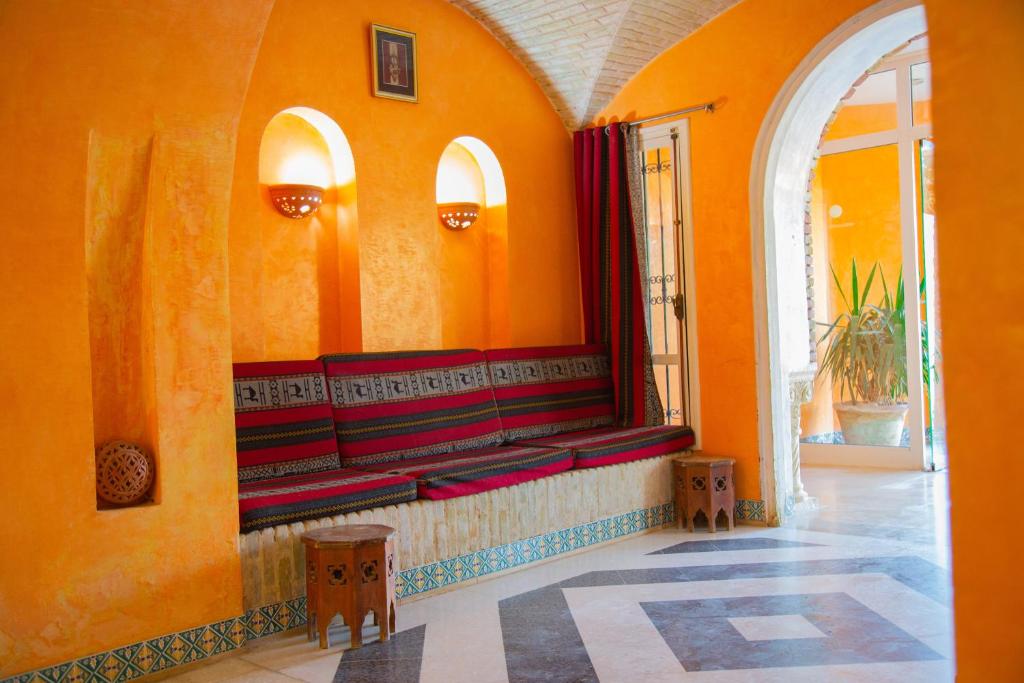 an orange wall with benches in a room with a window at Résidence El Arich in Tozeur