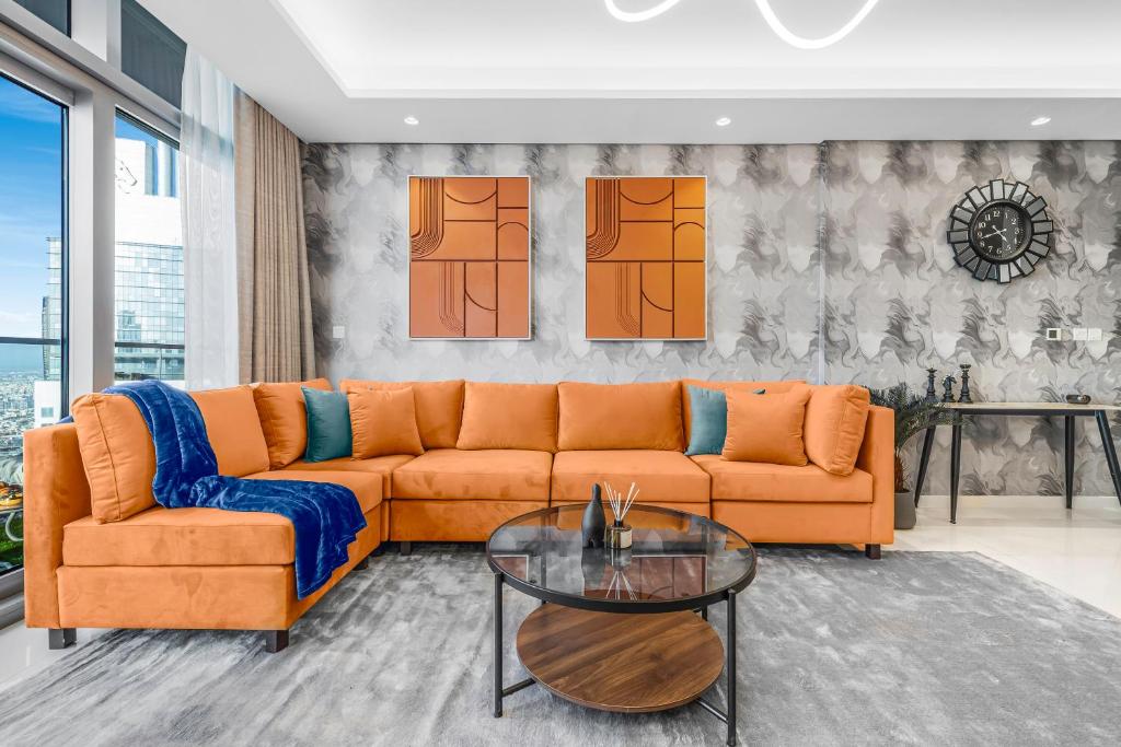 a living room with an orange couch and a glass table at 64th floor Skyline Pool with Burj Khalifa View in Paramount Hotel Midtown in Dubai