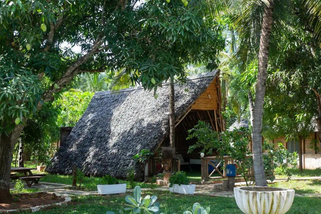 eine Hütte mit einem Strohdach im Garten in der Unterkunft Charming Cottage in Chumani, Kilifi County in Roka