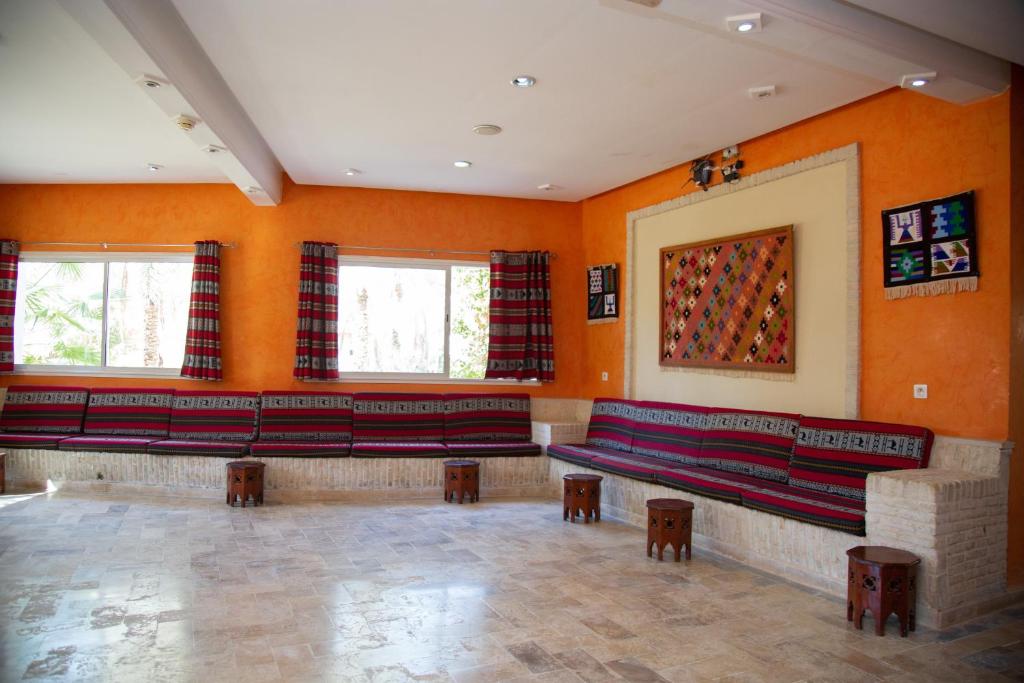 a waiting room with red benches and orange walls at Résidence El Arich in Tozeur
