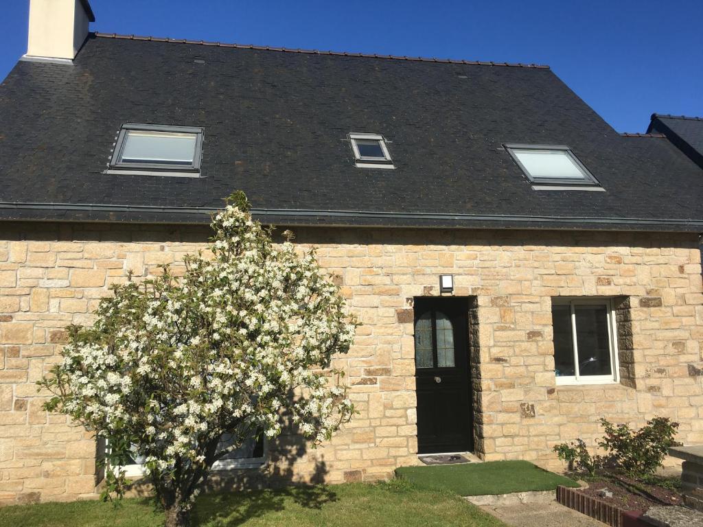 une maison en briques avec un arbre à fleurs devant elle dans l'établissement Chambre au calme avec salle d'eau entre le centre de Vannes et la forêt de Saint Avé, à Vannes