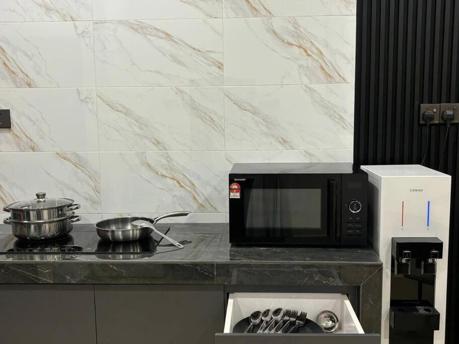 a kitchen with a microwave and a stove with pots and pans at 3 Story House With Jacuzzi PlyGround 18Pax Melaka Town 10min Jonker in Tranquerah