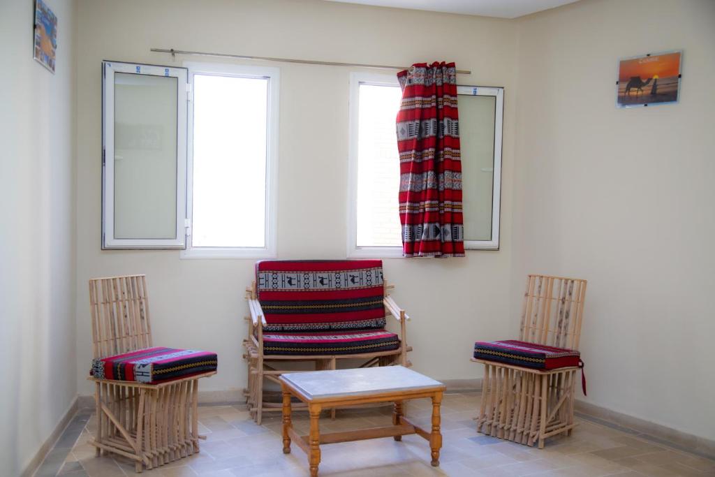 a room with chairs and a table and windows at Résidence El Arich in Tozeur