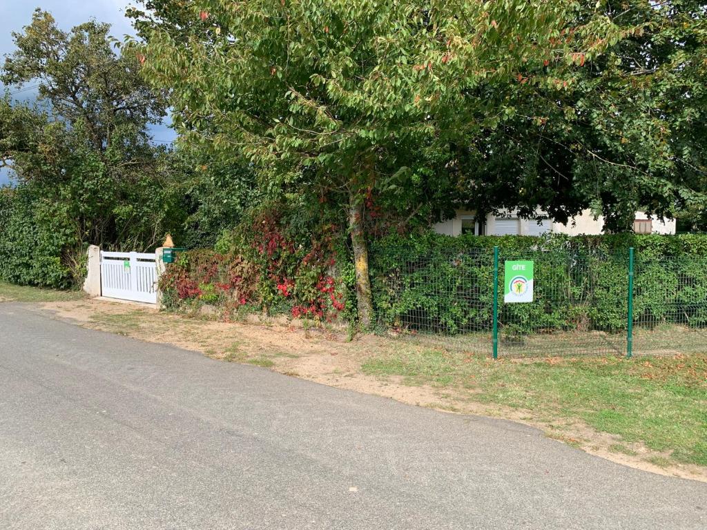 a fence with a tree and a sign on the side of a street at Chez Suzanne in Saint-Père-sur-Loire