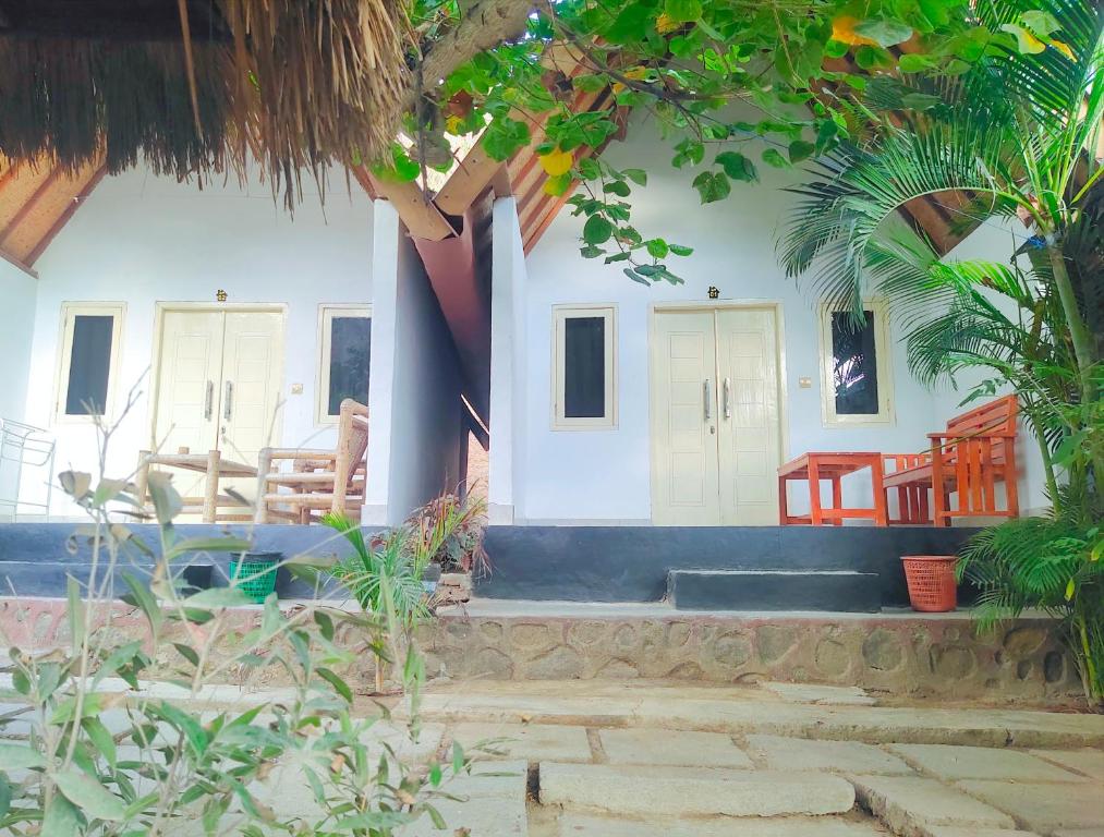 a house with a porch with chairs and trees at Putri Nyale Bungalows & Rooms in Kuta Lombok