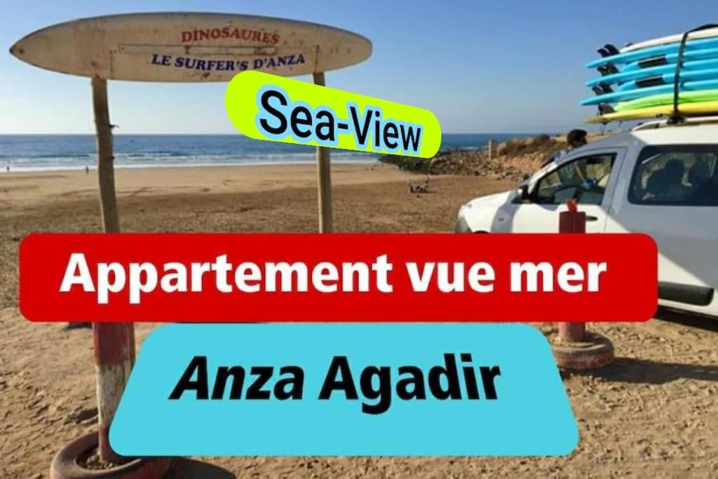 un cartello su una spiaggia con una tavola da surf sopra di Sun And Sea Appartement Anza Agadir ad Agadir