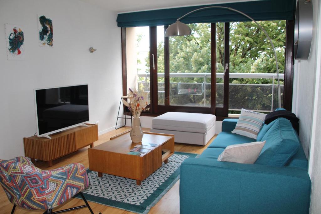 un salon avec un canapé bleu et une télévision dans l'établissement Nid Douillet à 15 min à pied du Lac, à Annecy