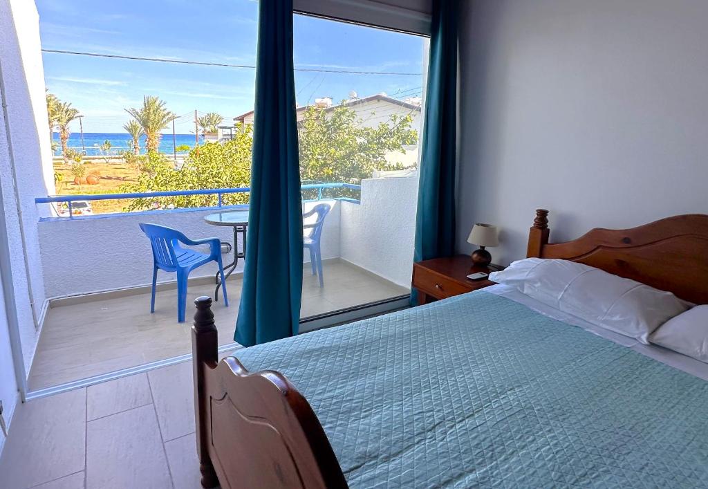a bedroom with a bed and a balcony with a table and chairs at Seafront Escape in Latchi in Polis Chrysochous