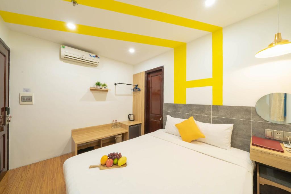 a bedroom with a bed and a desk with a bowl of fruit on it at Happy Day Riverside Hotel & Spa Danang by Haviland in Danang
