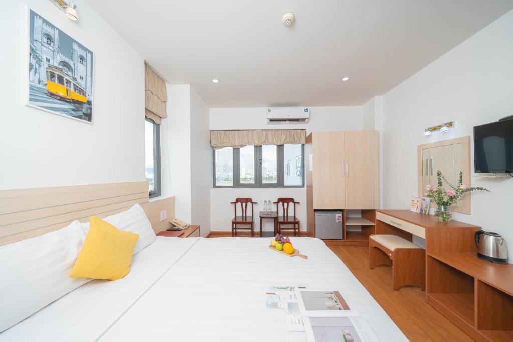 a bedroom with a large white bed and a desk at Happy Day Riverside Hotel & Spa Danang by Haviland in Danang