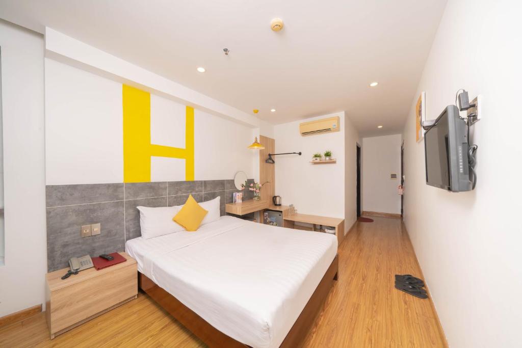 a bedroom with a white bed and a tv at Happy Day Riverside Hotel & Spa Danang by Haviland in Danang