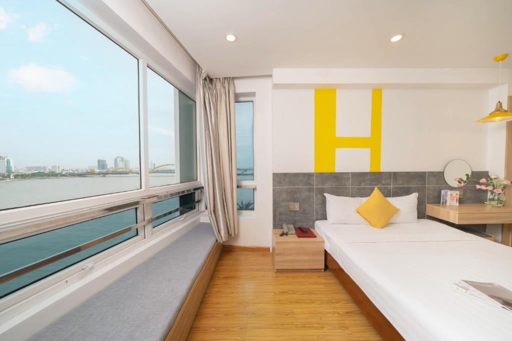 a bedroom with a bed and a large window at Happy Day Riverside Hotel & Spa Danang by Haviland in Danang