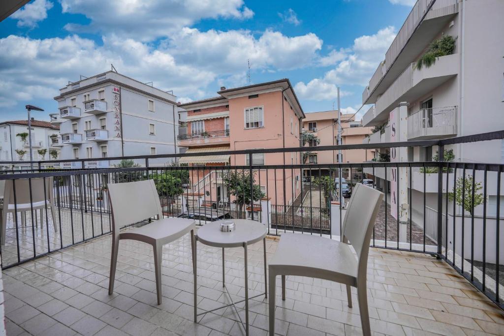 balkon ze stołem, krzesłami i budynkami w obiekcie SOMA w Rimini