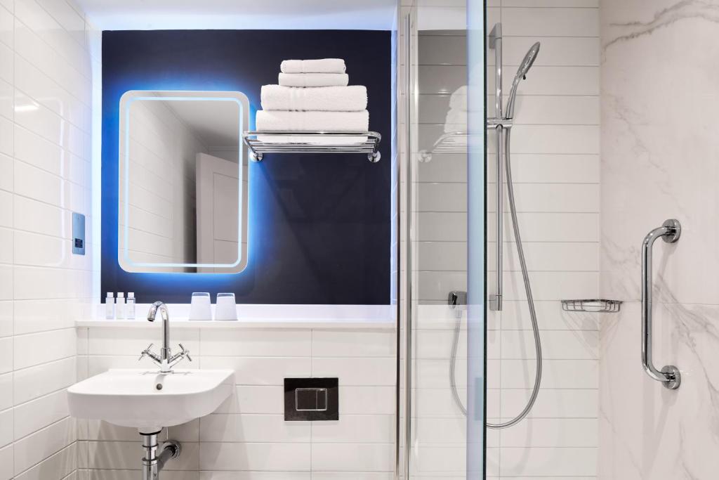a bathroom with a sink and a shower with a mirror at Strand Palace in London