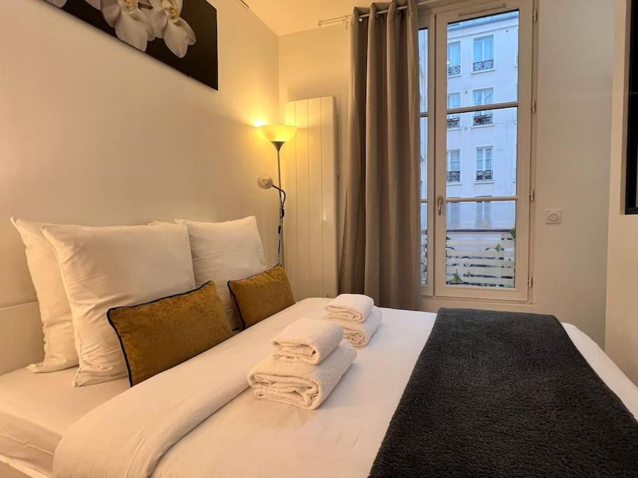 une chambre avec un lit avec des serviettes dessus dans l'établissement Grand Studio 2 pers République Bastille Paris 3, à Paris