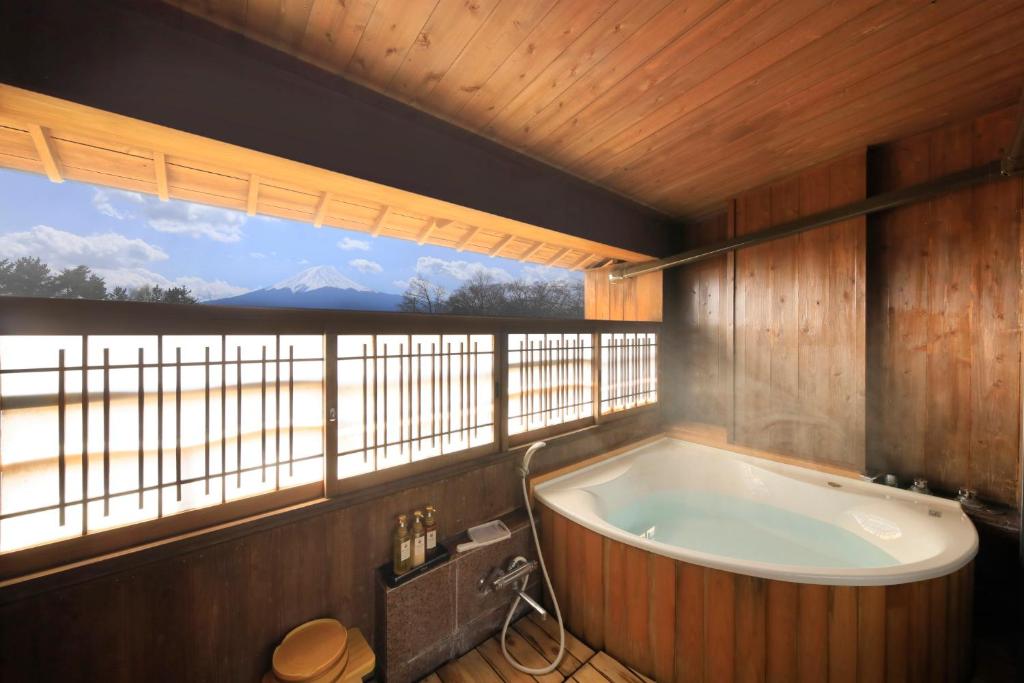 une baignoire dans une pièce avec une grande fenêtre dans l'établissement Lakeland Hotel Mizunosato, à Fujikawaguchiko