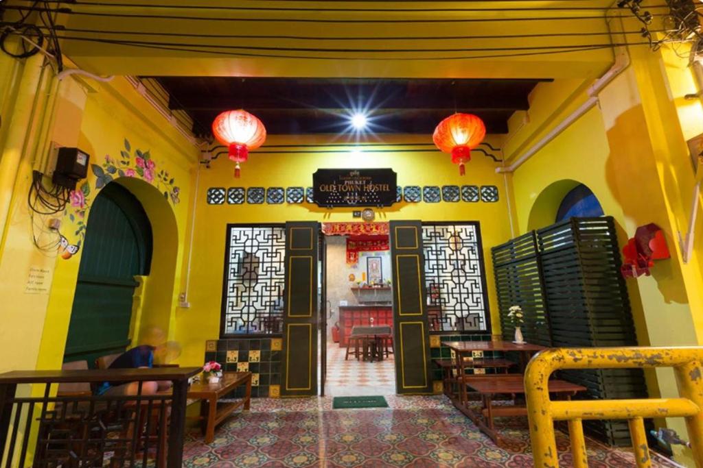 a restaurant with yellow walls and tables and lanterns at Phuket Old Town Hostel in Phuket Town