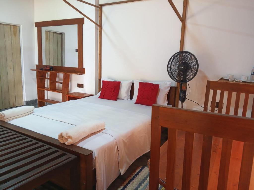 um quarto com uma cama com almofadas vermelhas e uma ventoinha em Turn View Resort Ella em Ella