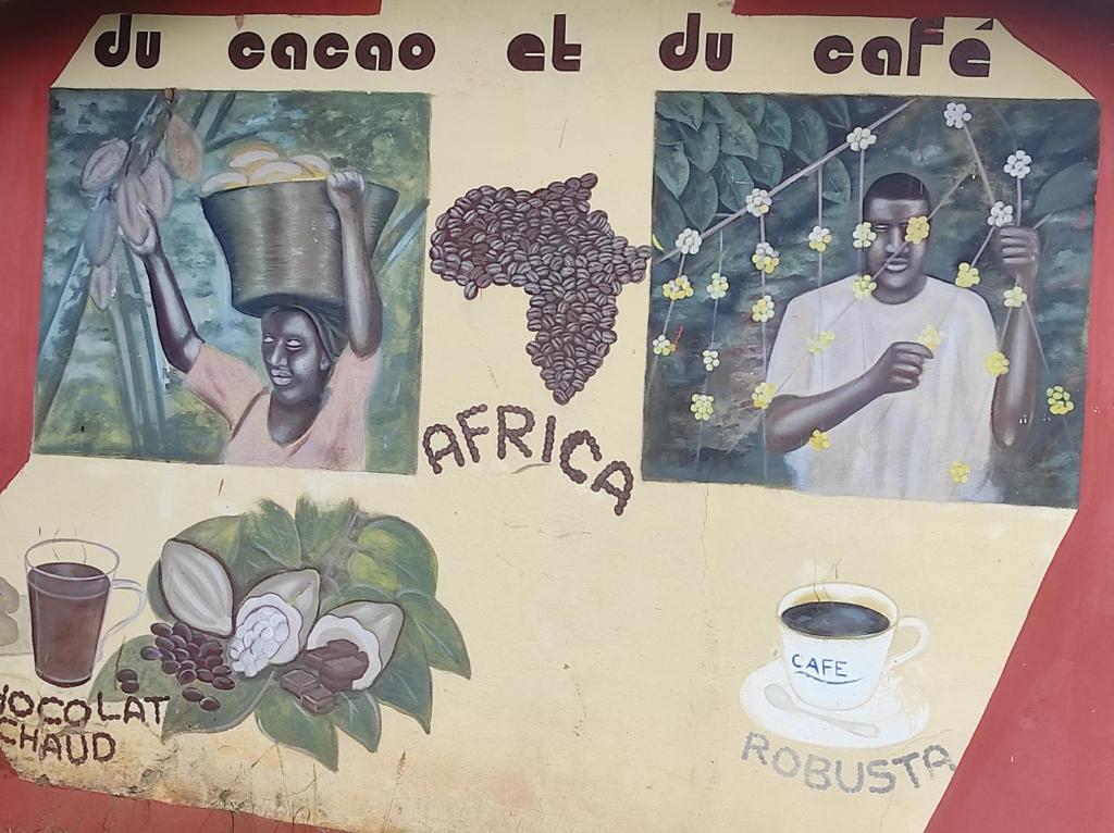 a sign with a painting of a man holding a pot of coffee at La montagne verte in Palimé