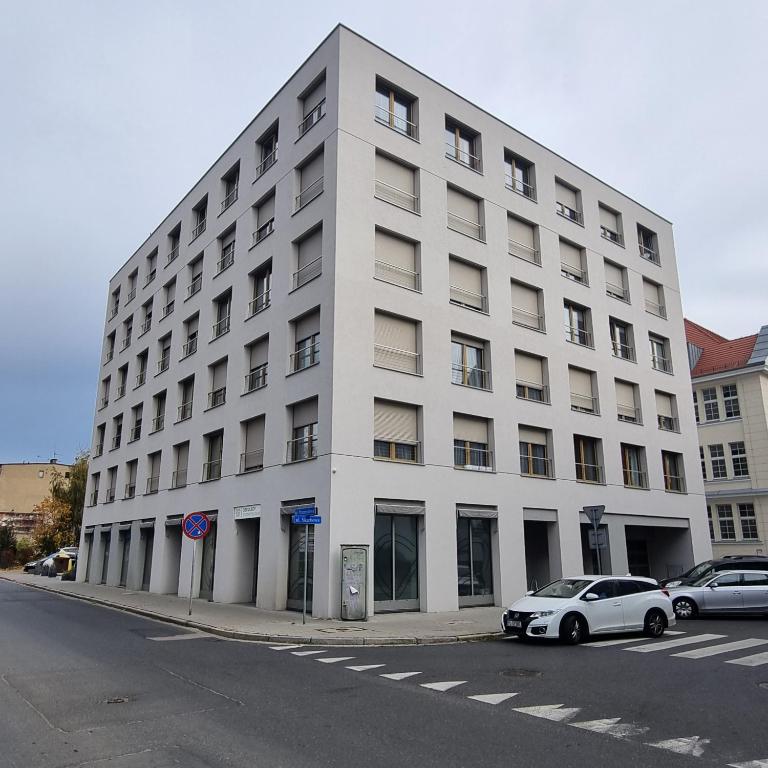 a white building with cars parked in front of it at Apartament Skarbowa Star in Leszno