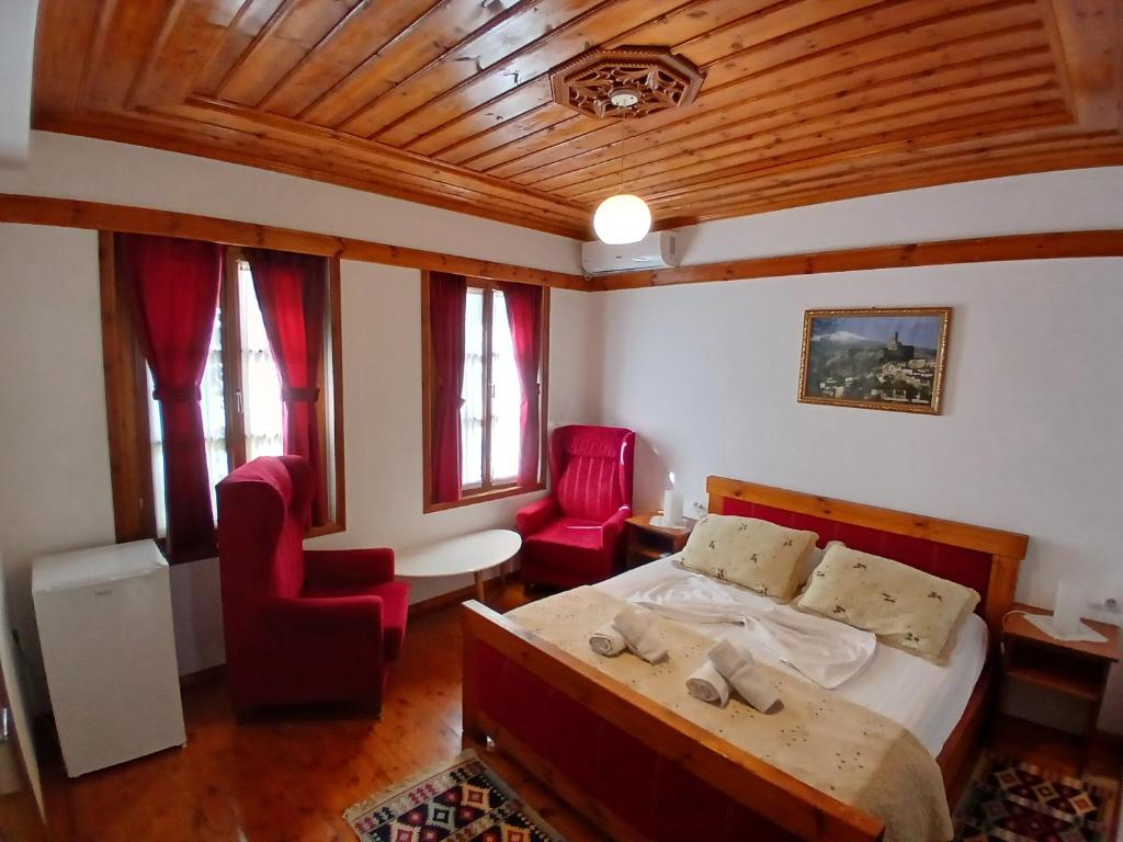 - une chambre avec un lit et deux chaises rouges dans l'établissement Amaris Hotel, à Gjirokastër