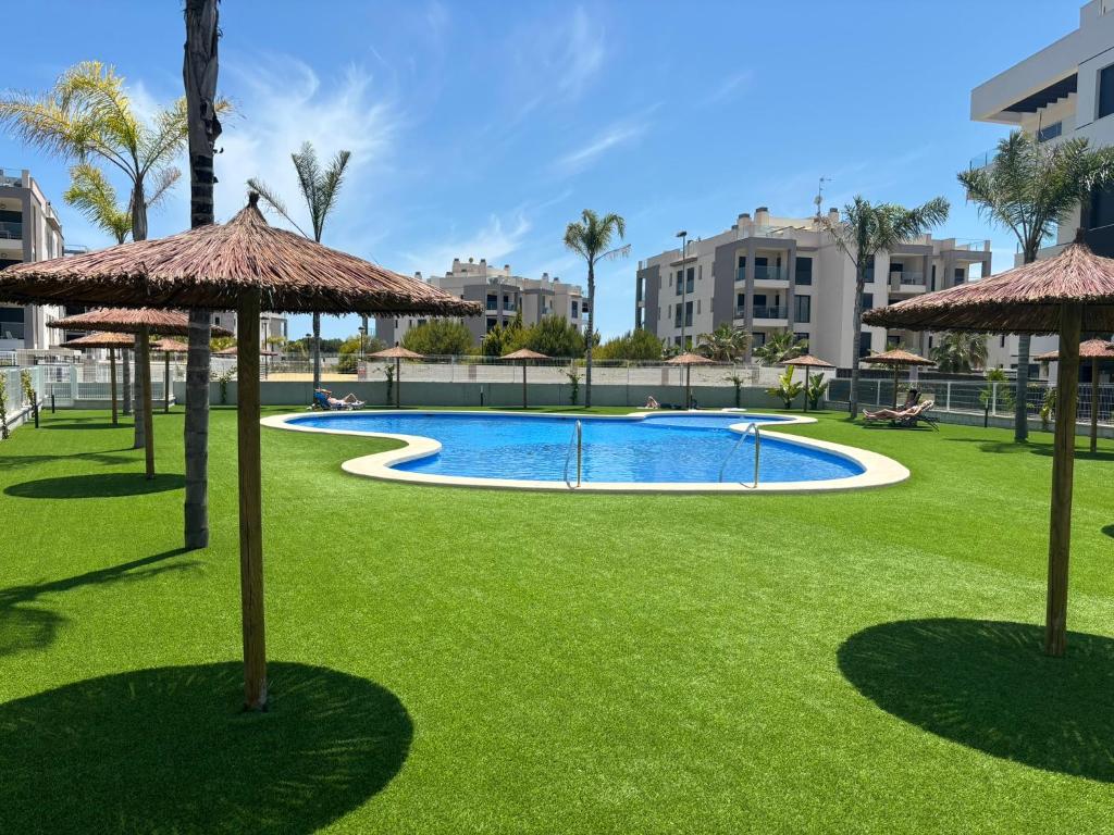 a swimming pool with umbrellas on the grass at Cosy Casa Valentino in Orihuela Costa