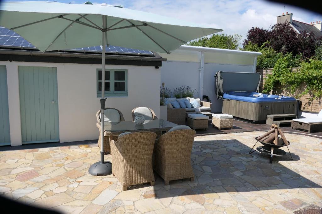 un patio avec une table et un parasol dans l'établissement maison 3 chambres spa centre Morgat, les plages et les restaurants a pied, à Crozon