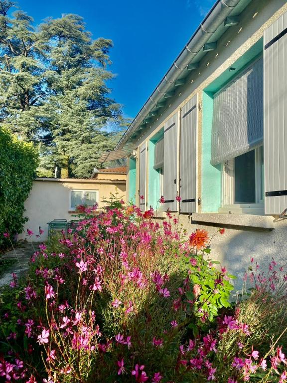 une maison avec des fleurs roses devant elle dans l'établissement La villa, au Vigan